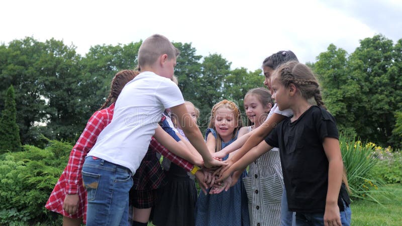Travail d'équipe d'enfants. Un groupe d'enfants heureux ensemble main dans la main. Équipe extérieure dans le parc banque de vidéos