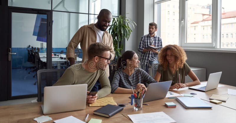 Travail d'équipe. Groupe de jeunes hommes d'affaires multiculturelles heureux en travaillant ensemble au bureau moderne communiqua photos stock