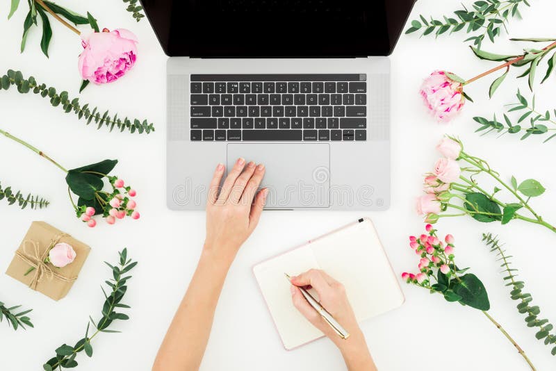 Travail de femme avec l'ordinateur portable Espace de travail avec les mains femelles, l'ordinateur portable, le carnet et les fl photo libre de droits Travail de femme avec l'ordinateur portable Espace de travail avec les mains femelles, l'ordinateur portable, le carnet et les fl photo libre de droits