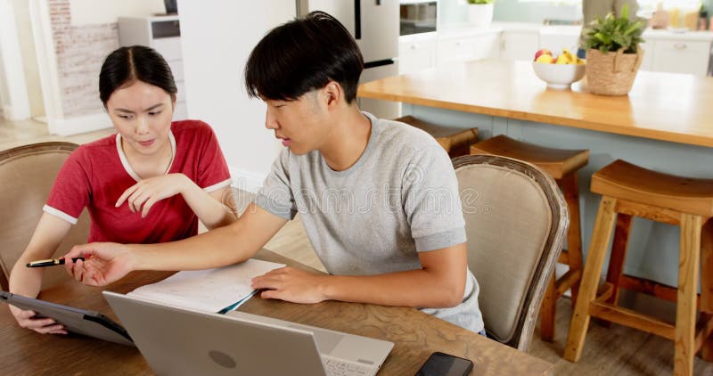 Travailler à partir d'un couple à domicile en utilisant un ordinateur portable et une tablette lors de la discussion de documents banque de vidéos