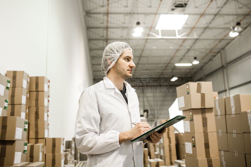 Travailleur dans l'entrepôt pour l'emballage alimentaire photographie stock libre de droits Travailleur dans l'entrepôt pour l'emballage alimentaire photographie stock libre de droits