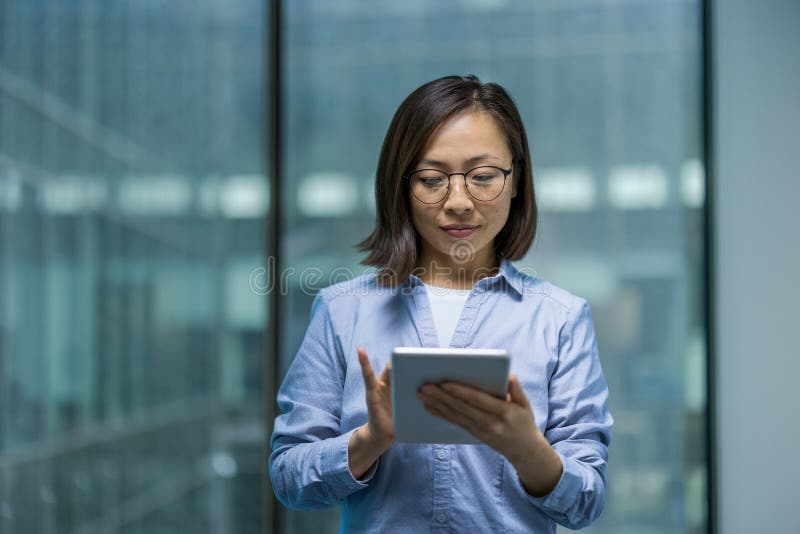 Travailleur de bureau sérieux et confiant utilisant un ordinateur tablette. Une femme d'affaires asiatique utilisant l'application photographie stock libre de droits