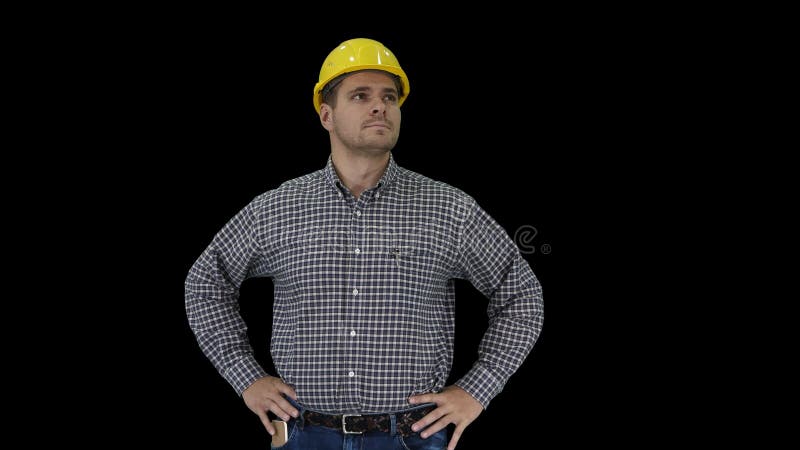 Travailleur de construction souriant dans un casque jaune regardant un objet parfait bien construit Mains sur les hanches, canal A banque de vidéos