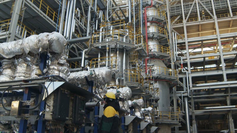 Travailleur de vue de côté au panneau de commande au complexe de raffinerie de pétrole banque de vidéos