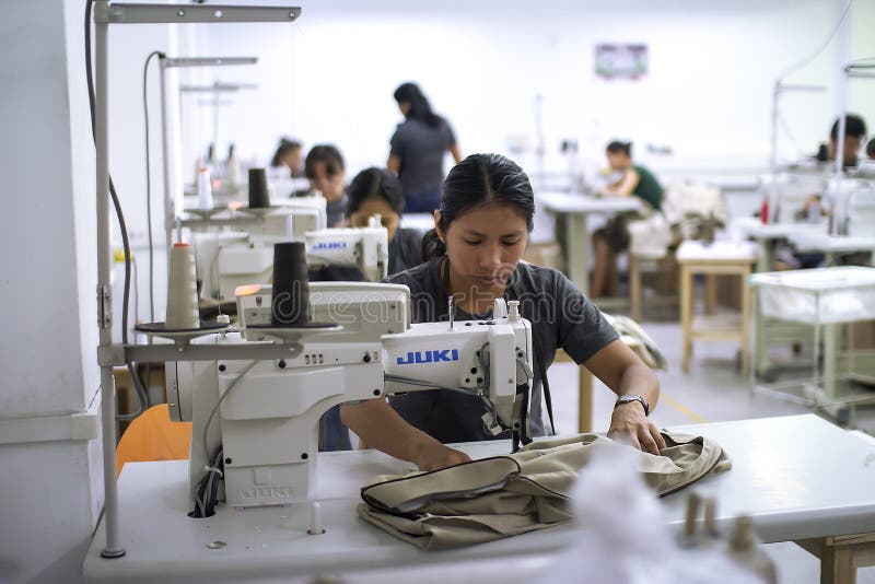 Travailleur hispanique féminin avec la machine à coudre apportant des changements aux vêtements photos stock Travailleur hispanique féminin avec la machine à coudre apportant des changements aux vêtements photos stock