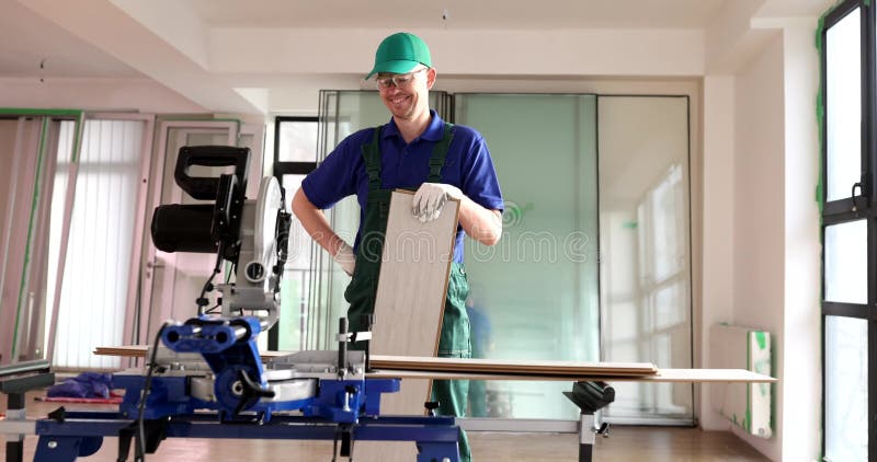 Travailleur souriant tient des planches pour la pose de parquet avec machine à scier clips vidéos