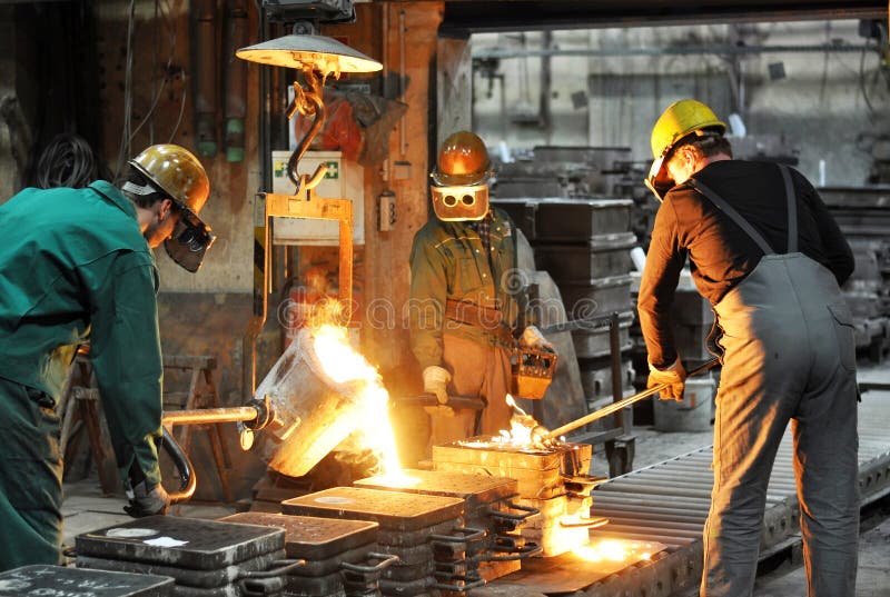Travailleurs dans une fonderie moulant un objet en métal - sécurité au travail et travail d'équipe
