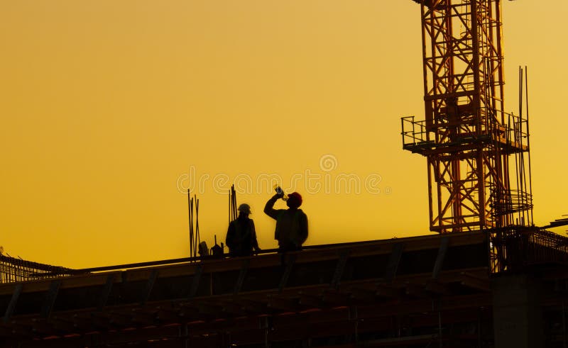 Travailleurs de la construction sur le chantier au coucher du soleil images libres de droits Travailleurs de la construction sur le chantier au coucher du soleil images libres de droits