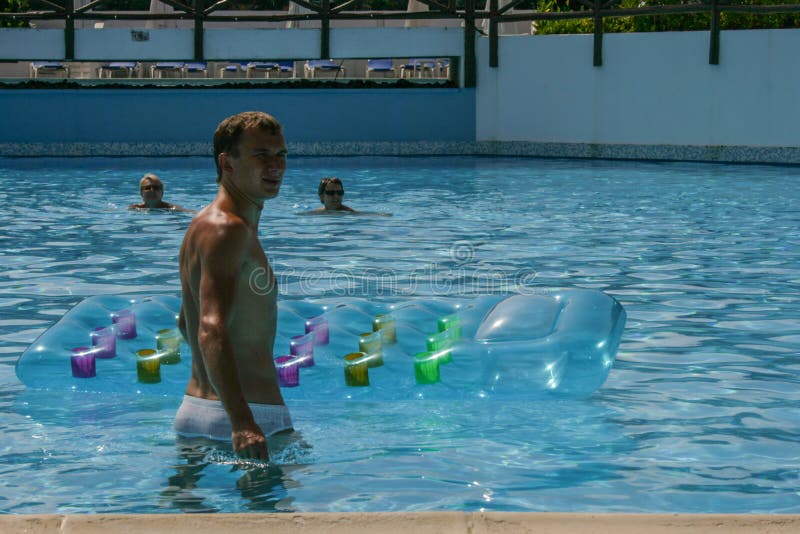 Travel around Greece. a young man swims on a water mattress in a blue water pool royalty free stock images Travel around Greece. a young man swims on a water mattress in a blue water pool royalty free stock images