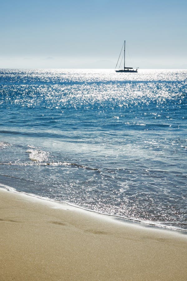 Travel background with sand of the beach, blue sea and silhouette of a sailing boat stock images Travel background with sand of the beach, blue sea and silhouette of a sailing boat stock images