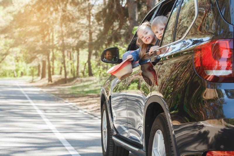 Travel by car family ride together brother and sister lean out of the window. Travel by car family ride together brother and sister lean out of the window