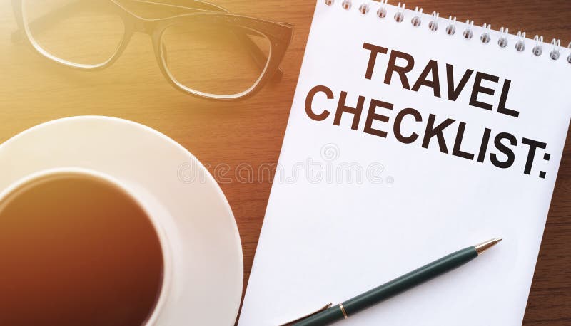 TRAVEL CHECKLIST - text on paper with cup of coffee and glasses on wooden background in sinlight