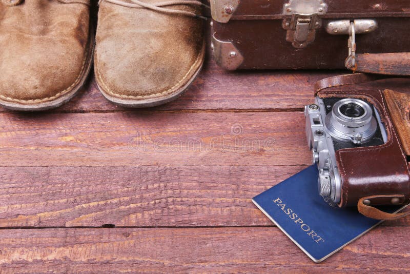 Travel concept with Vintage suitcase, sunglasses, old camera, suede boots, case for money and passport on wooden floor.