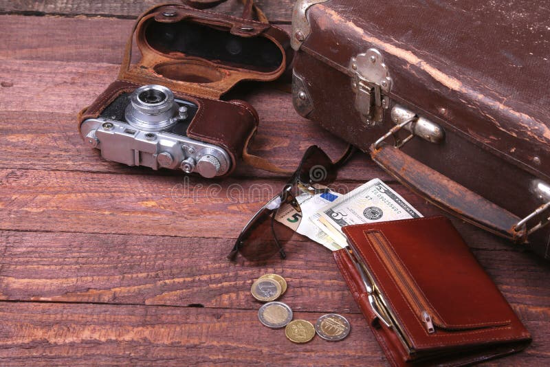 Travel concept with Vintage suitcase, sunglasses, old camera, suede boots, case for money and passport on wooden floor. Ancient, elegant.