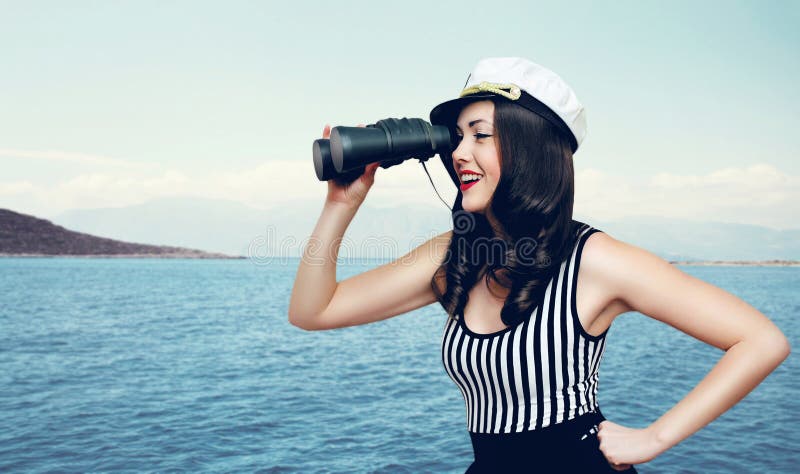 Travel, cruise, tourism and adventure concept - pretty smiling woman of a sailor looking through binoculars against the sea and island