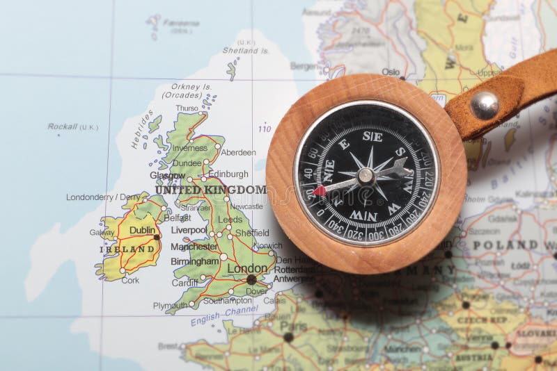 Compass on a map pointing at United Kingdom and Ireland, planning a travel destination. Compass on a map pointing at United Kingdom and Ireland, planning a travel destination