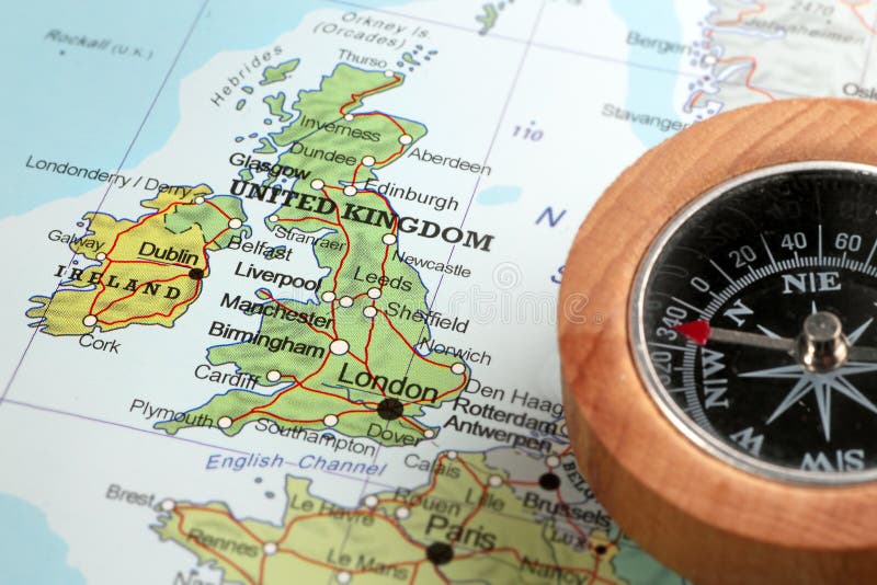 Compass on a map pointing at United Kingdom and Ireland, planning a travel destination. Compass on a map pointing at United Kingdom and Ireland, planning a travel destination