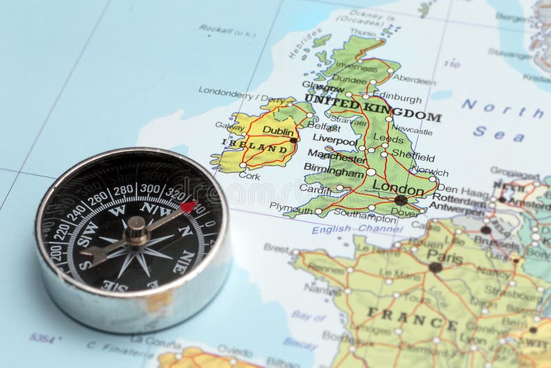 Compass on a map pointing at United Kingdom and Ireland, planning a travel destination. Compass on a map pointing at United Kingdom and Ireland, planning a travel destination