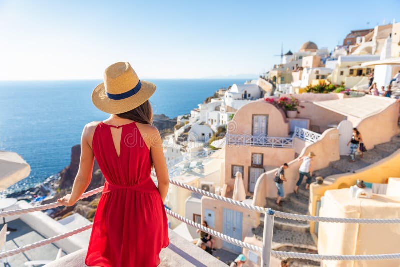 Travel vacation greece santorini island woman in red dress traveling in Europe looking at Oia village view, luxury