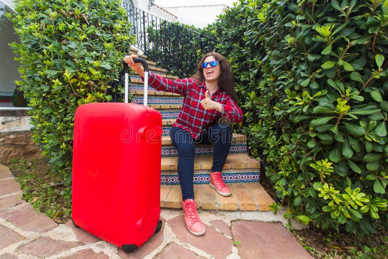 Travel, vacations and holidays concept - happy traveller woman sitting on stairs in sunny glasses with red suitcase and stock photos Travel, vacations and holidays concept - happy traveller woman sitting on stairs in sunny glasses with red suitcase and stock photos