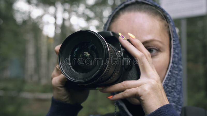 Traveler photographing scenic view in forest. One caucasian woman shooting close up look. Girl take photo video on dslr mirrorless camera. Professional photographer travel with backpack. Outdoor. Traveler photographing scenic view in forest. One caucasian woman shooting close up look. Girl take photo video on dslr mirrorless camera. Professional photographer travel with backpack. Outdoor.