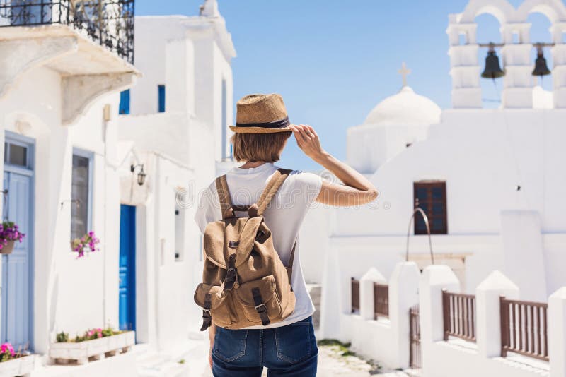 Traveler girl enjoying vacations in Greece. Young woman wearing hat looking at greek village. Summer holidays, vacations, travel