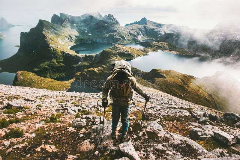 Traveler man climbing to Hermannsdalstinden mountain top in Norway