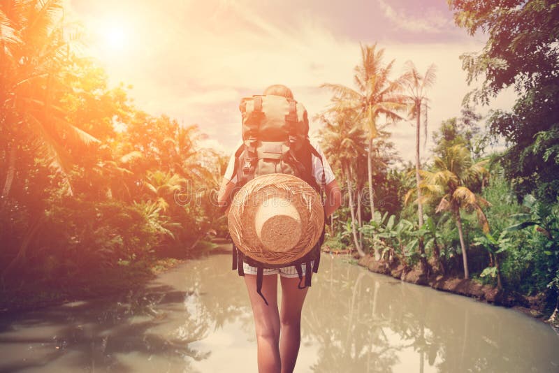 Traveler woman with backpack standing near big tropical river