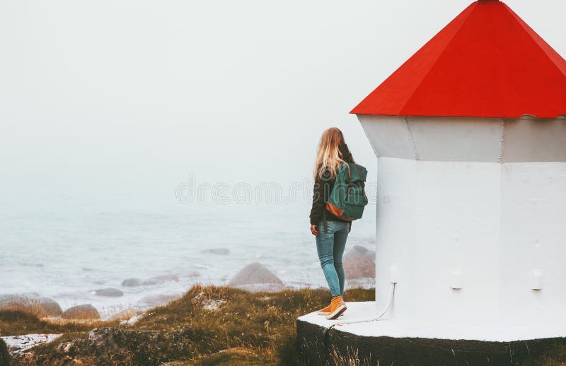 Traveler woman and lighthouse at foggy sea solo traveling lifestyle adventure scandinavian trip outdoor solitude emotions