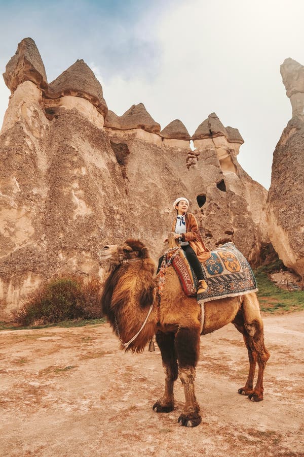 Traveler woman riding camel at Goreme fairy chimneys , Cappadocia. Nevsehir Province. Turkey royalty free stock photo Traveler woman riding camel at Goreme fairy chimneys , Cappadocia. Nevsehir Province. Turkey royalty free stock photo