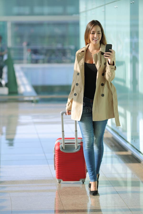 Traveler woman walking and using a smart phone in an airport