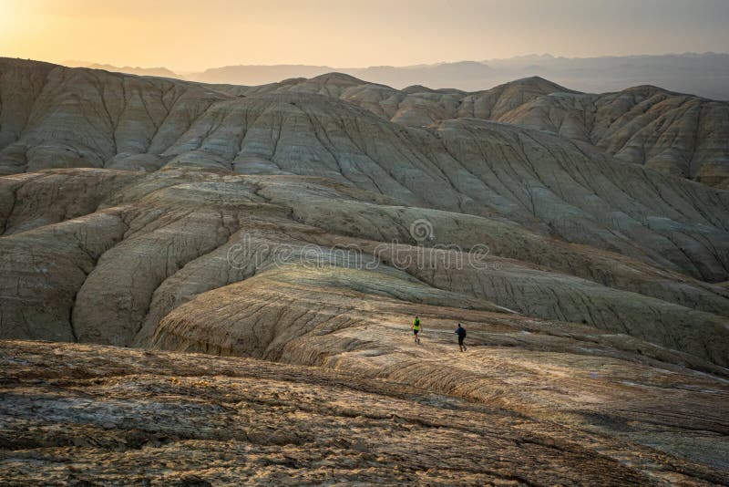 Travelers walk in the desert mountains in the evening. Altyn Emel National Park. Kazakhstan