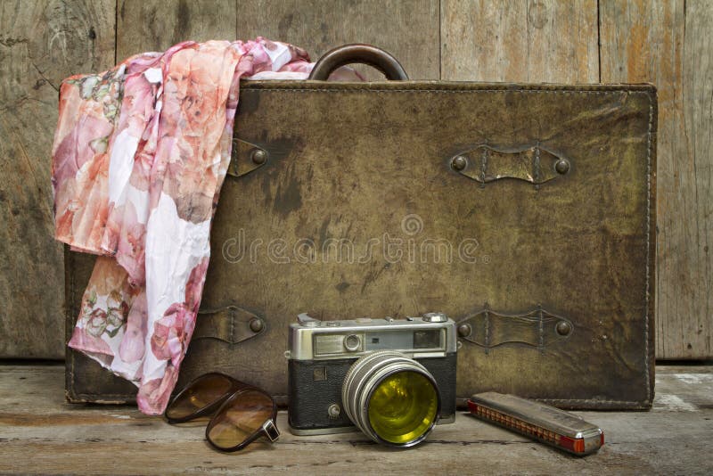 Traveling concept of retro consists suitcase, camera, sunglasses, mouth organ and shawl on wooden background