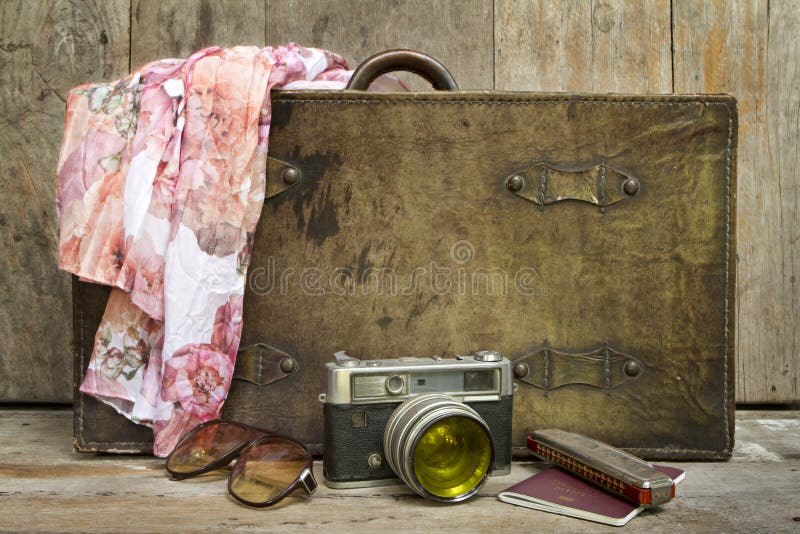 Traveling concept of retro consists suitcase, camera, sunglasses, mouth organ, shawl and on wooden background