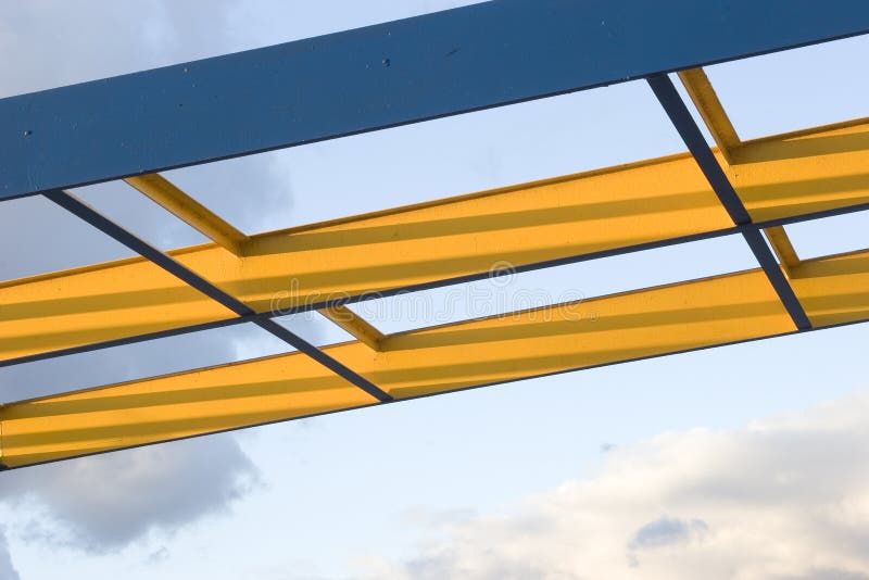 Blue and yellow steel beams against a cloudy sky. Blue and yellow steel beams against a cloudy sky