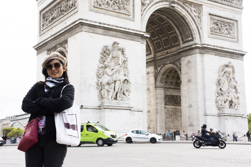 Travlers tailandeses asiáticos de la mujer que presentan con Arco del Triunfo de l ` Etoile o arco triunfal de la estrella imágenes de archivo libres de regalías Travlers tailandeses asiáticos de la mujer que presentan con Arco del Triunfo de l ` Etoile o arco triunfal de la estrella imágenes de archivo libres de regalías