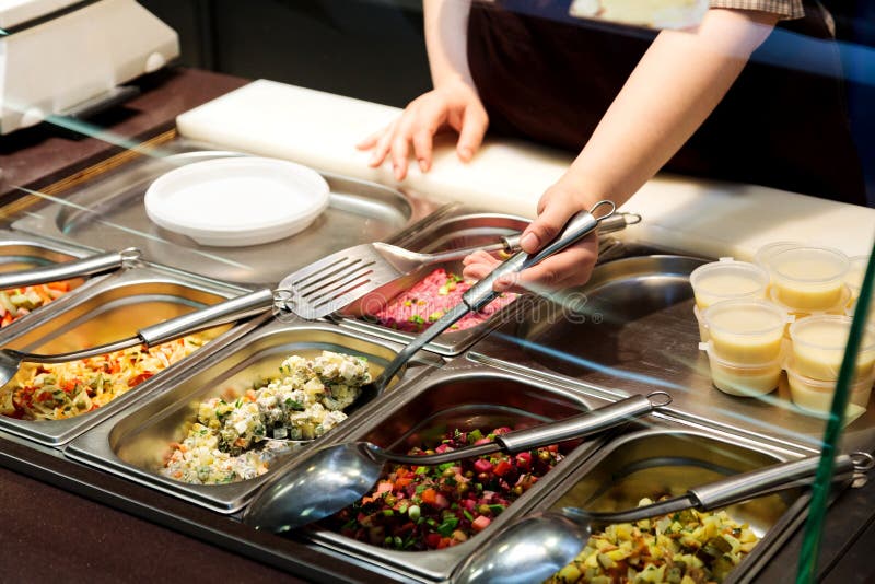 Trays with cooked food on showcase at cafeteria.