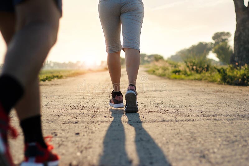 Traînée de femme de forme physique de jeunes fonctionnant sur la route rurale en été photos libres de droits Traînée de femme de forme physique de jeunes fonctionnant sur la route rurale en été photos libres de droits