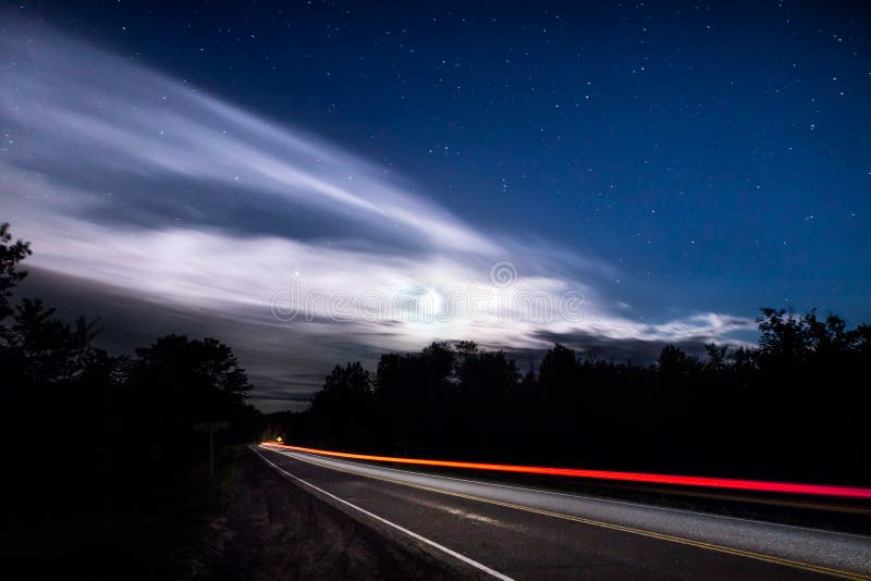 Traînée légère d'une voiture de dépassement sur une route rurale la nuit images libres de droits Traînée légère d'une voiture de dépassement sur une route rurale la nuit images libres de droits