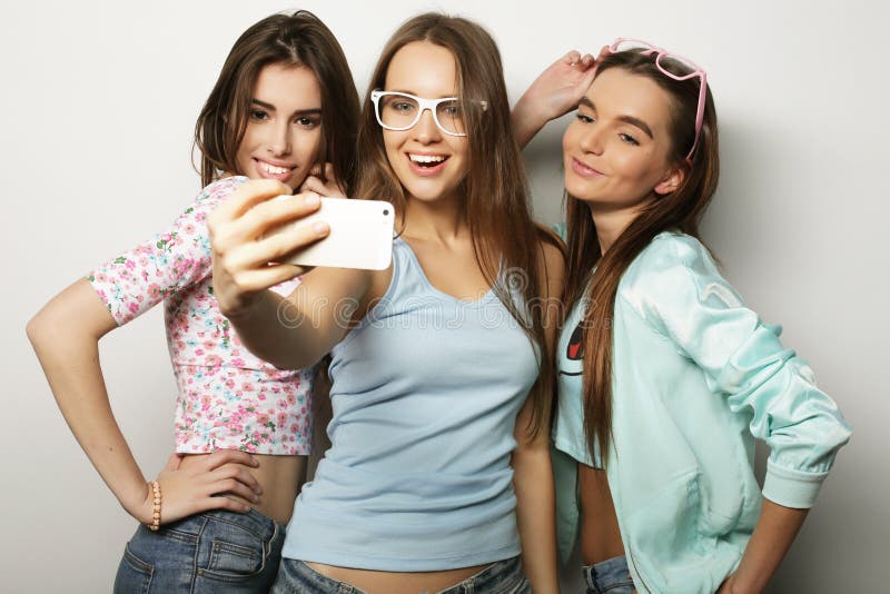 Tre adolescenti felici con lo smartphone che prende selfie fotografia stock Tre adolescenti felici con lo smartphone che prende selfie fotografia stock