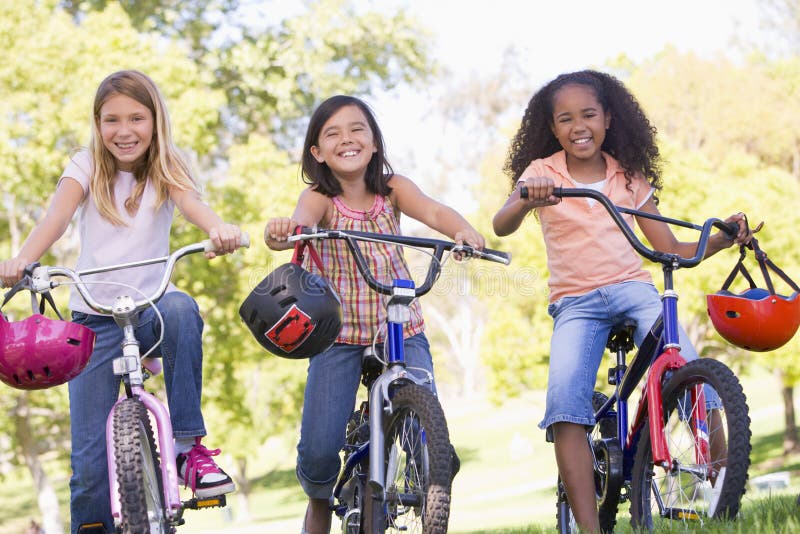 Tre amici della ragazza sul sorridere delle biciclette immagini stock libere da diritti Tre amici della ragazza sul sorridere delle biciclette immagini stock libere da diritti