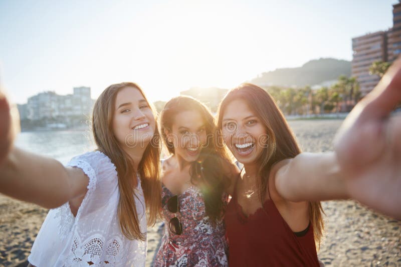 Tre amici femminili felici che prendono selfie sulla spiaggia fotografia stock libera da diritti Tre amici femminili felici che prendono selfie sulla spiaggia fotografia stock libera da diritti