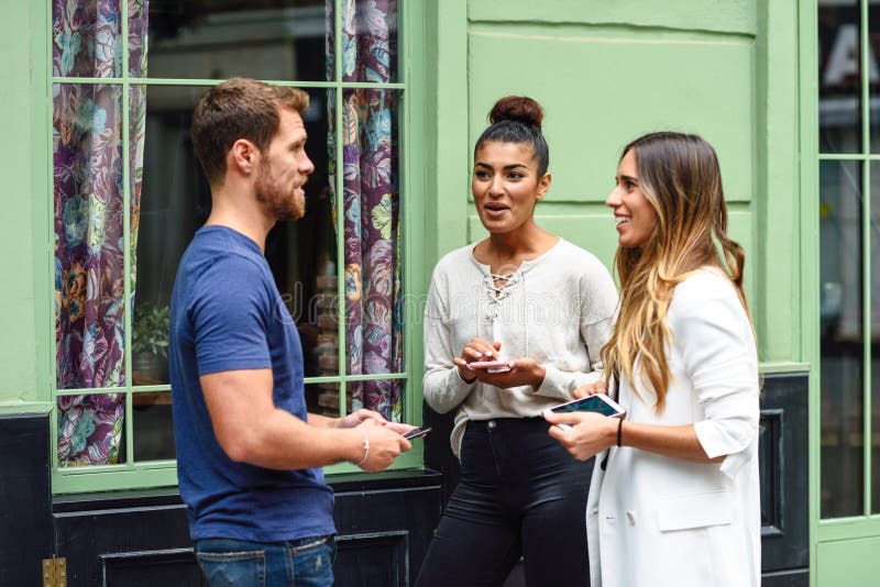Tre amici multietnici della gente che parlano e che sorridono all'aperto immagini stock Tre amici multietnici della gente che parlano e che sorridono all'aperto immagini stock