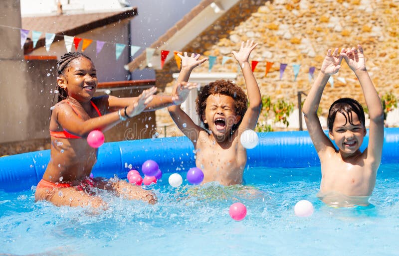 Tre bambini che ridono e urlano giocano in piscina fotografia stock