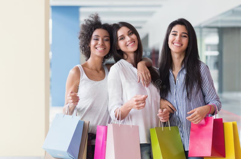 Tre belle donne con le borse colourful che camminano nel centro commerciale immagini stock Tre belle donne con le borse colourful che camminano nel centro commerciale immagini stock