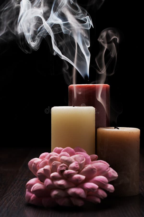 Tre candele con fumo sulla tavola di legno con fondo nero e un arrangment rosa del fiore Rembrandt che accende il Natale ispirato fotografie stock libere da diritti Tre candele con fumo sulla tavola di legno con fondo nero e un arrangment rosa del fiore Rembrandt che accende il Natale ispirato fotografie stock libere da diritti