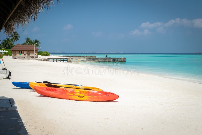 Tre canoe sulla spiaggia di sabbia bianca, pilastro di pietra sulla laguna del turchese in Maldive fotografia stock libera da diritti Tre canoe sulla spiaggia di sabbia bianca, pilastro di pietra sulla laguna del turchese in Maldive fotografia stock libera da diritti
