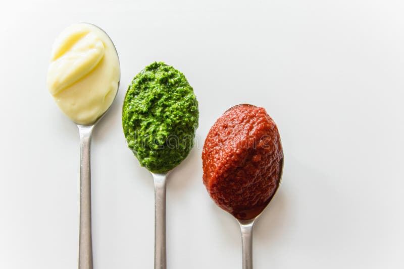 Tre cucchiai con differenti condimenti - maionese, salsa al pomodoro e pesto fotografie stock Tre cucchiai con differenti condimenti - maionese, salsa al pomodoro e pesto fotografie stock