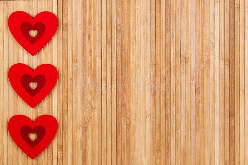 Tre cuori rossi su un fondo di legno, un giorno forte del ` s del biglietto di S. Valentino della carta fotografia stock Tre cuori rossi su un fondo di legno, un giorno forte del ` s del biglietto di S. Valentino della carta fotografia stock