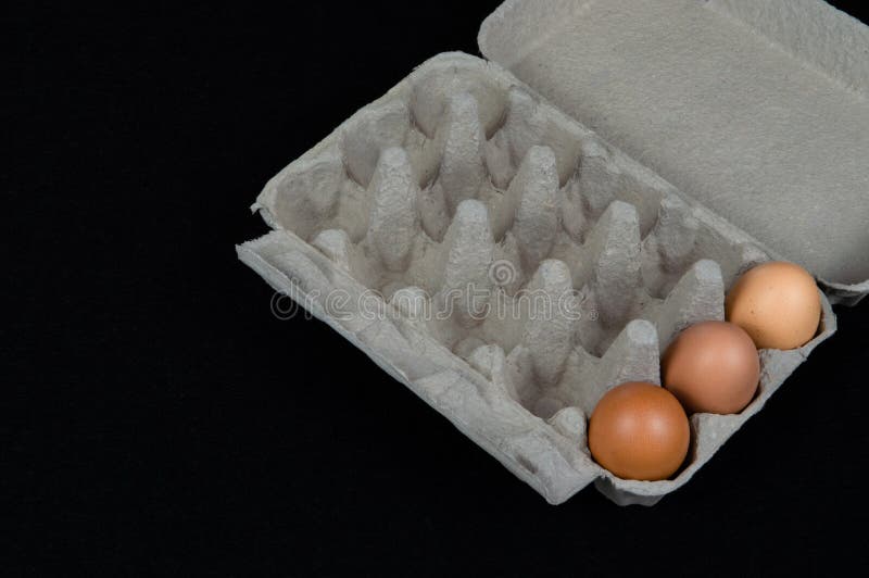 Tre fega ägg i en lådaask som isoleras på svart matt bakgrund arkivbilder Tre fega ägg i en lådaask som isoleras på svart matt bakgrund arkivbilder